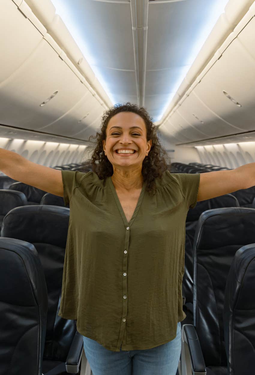 woman smiling while standing in plane aisle