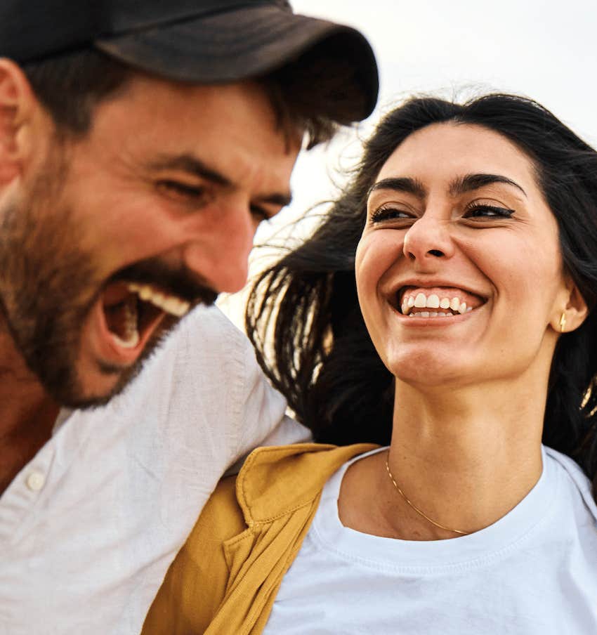 Laughing man and smiling woman compliment each other