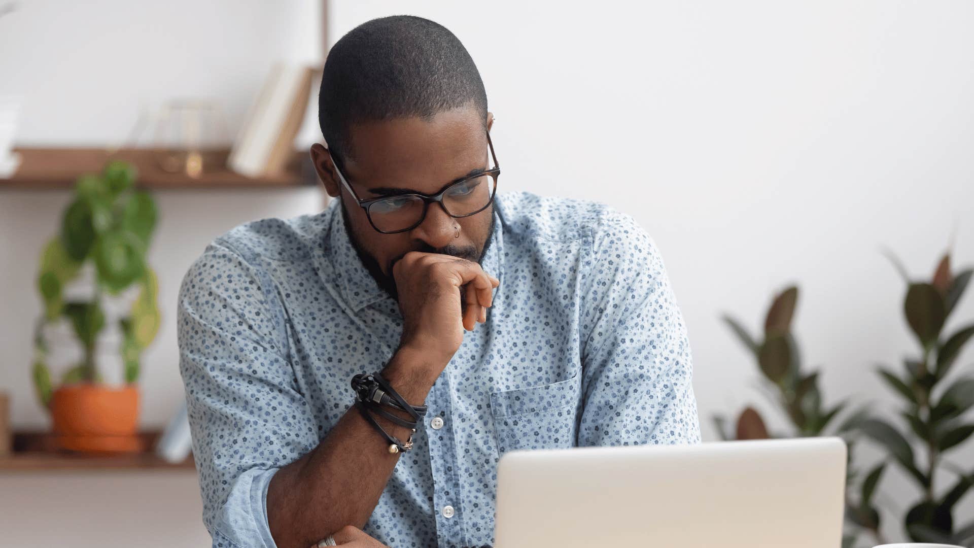 man looking at laptop with hand covering man