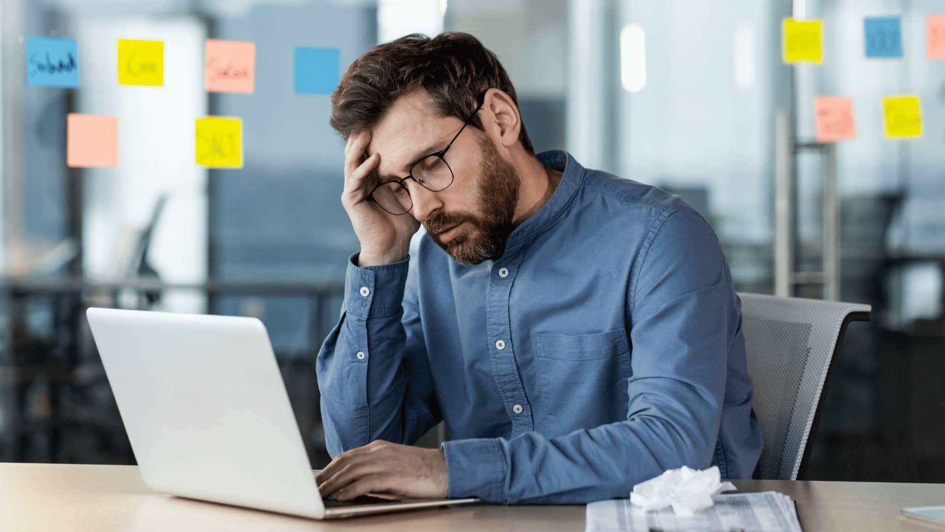 Man looking stressed while staring at laptop 