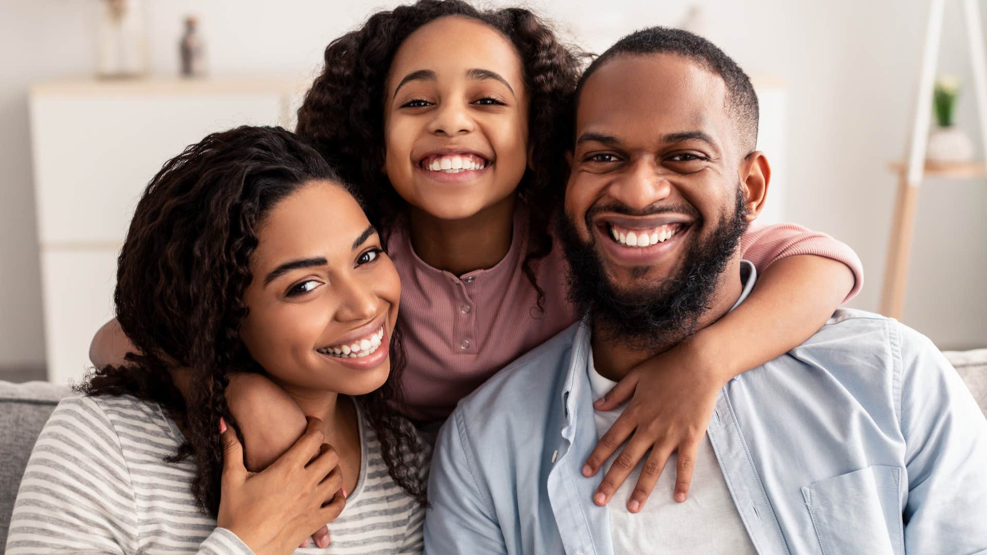 Young girl smiling and hugging her two parents. 