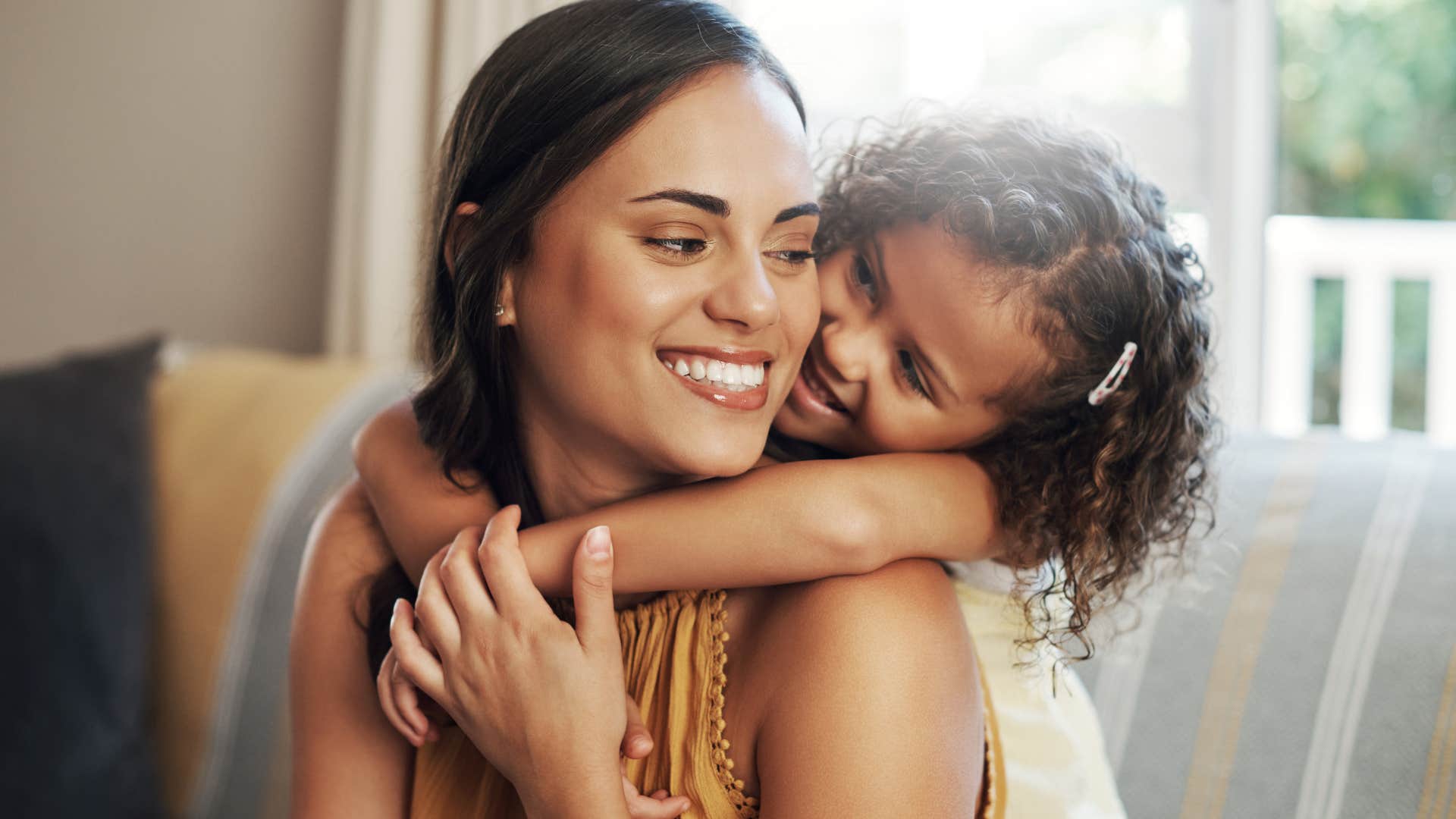 Woman smiling and hugging her young daughter.