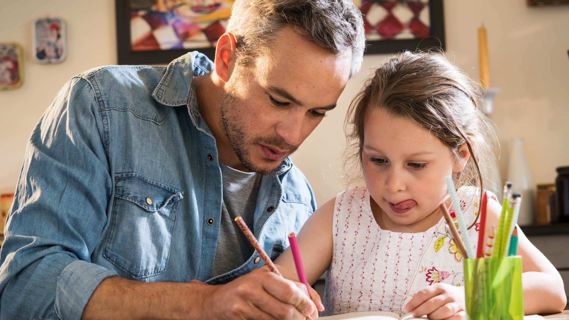 Man helping his young daughter with homework.