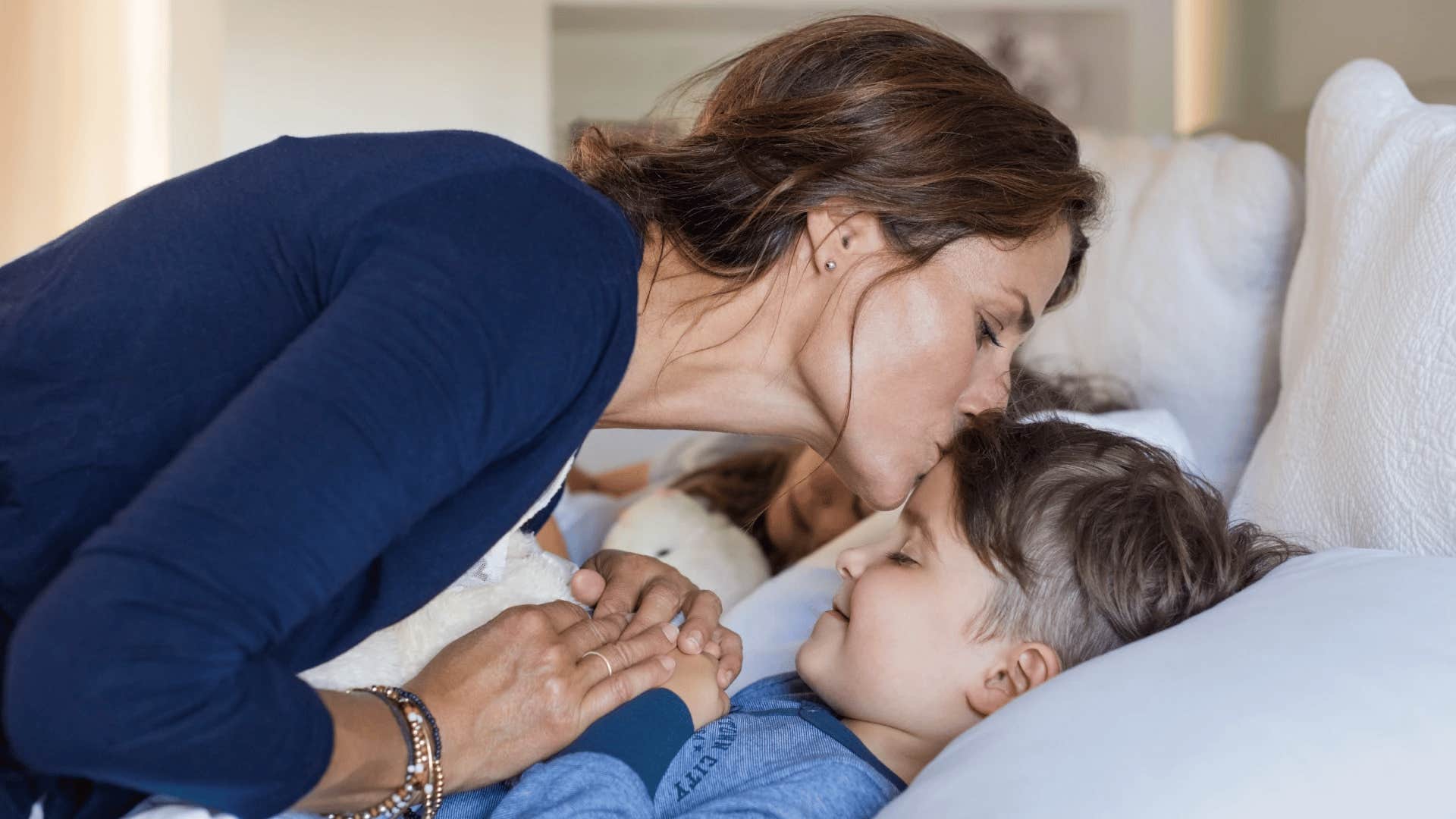 mother tucking son in for early bedtime