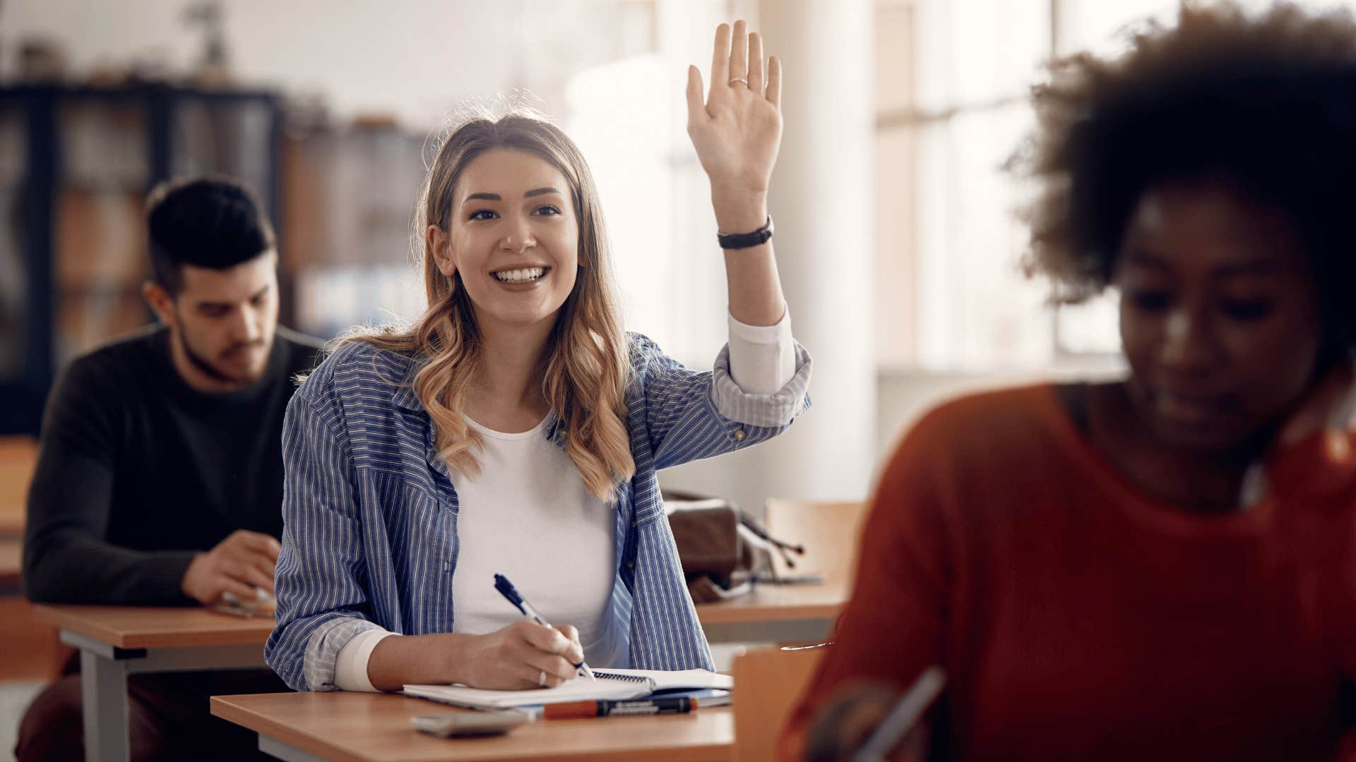 woman raising hand while sitting in class