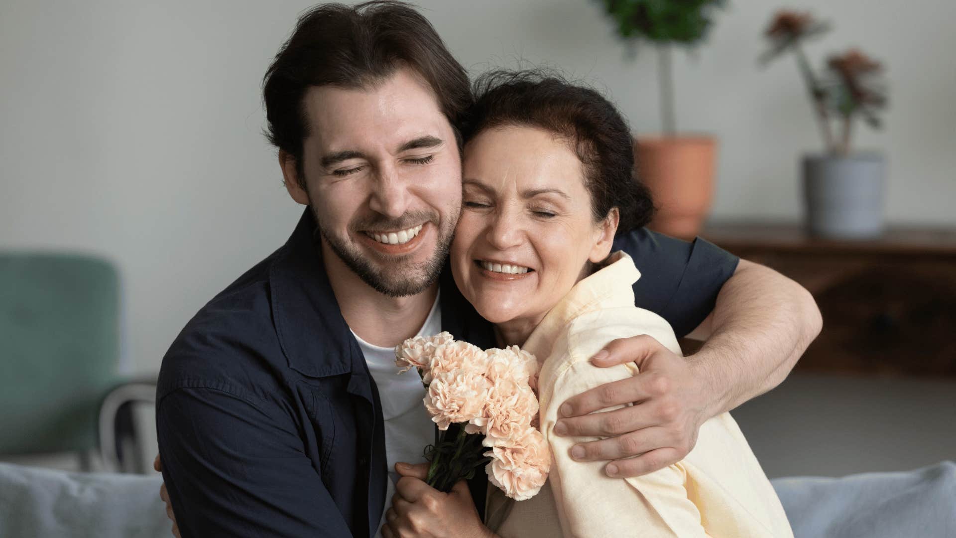 son hugging mother giving her flowers