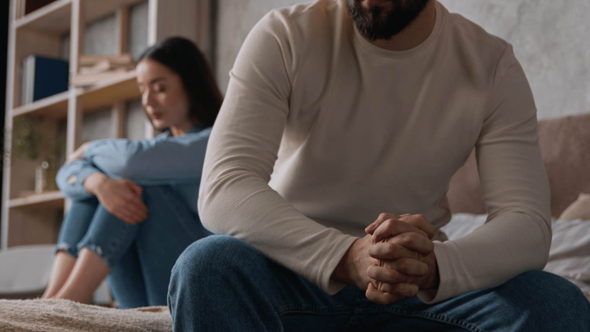 couple sitting away from each other on bed