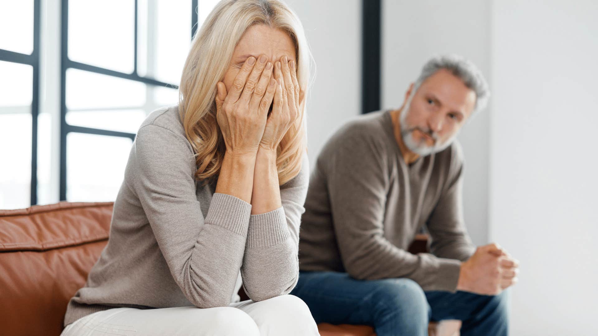 upset woman sitting next to man on couch