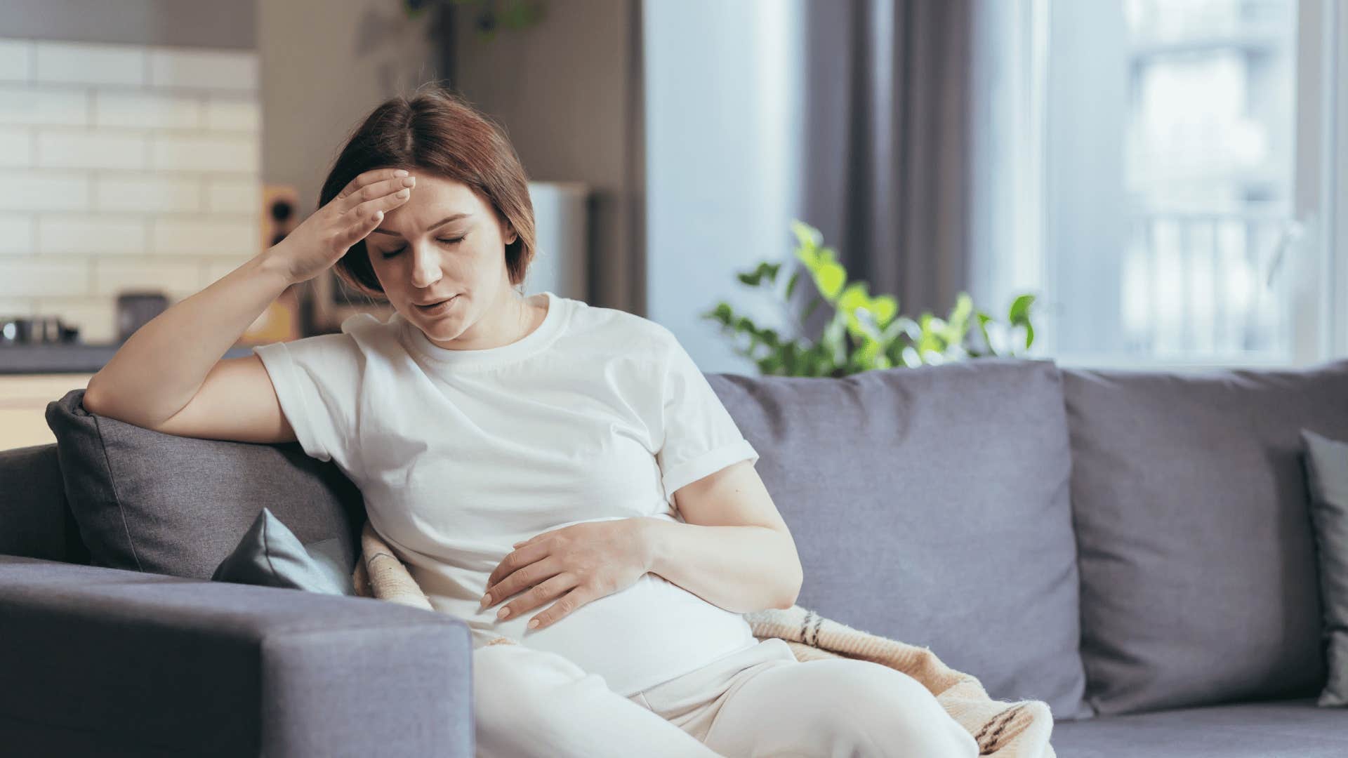 woman sitting on couch feeling sick