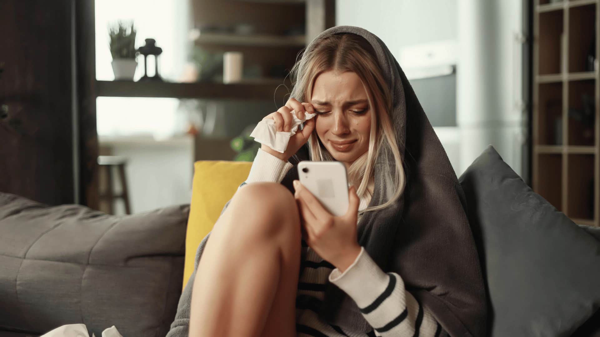 woman crying while looking at phone