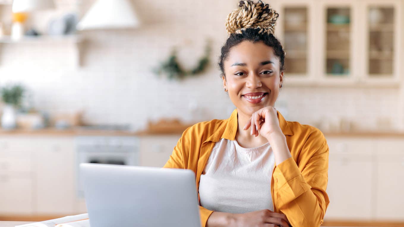 businesswoman smiling while working on laptop at desk in home office