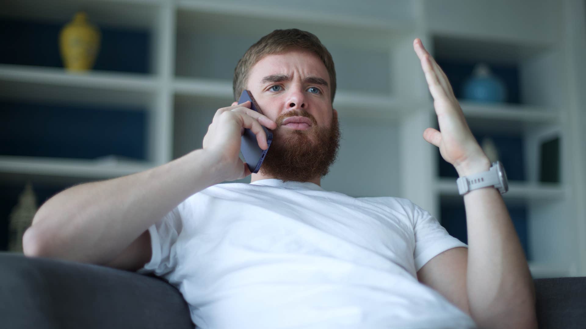 Frustrated man holding his hands up while talking on the phone