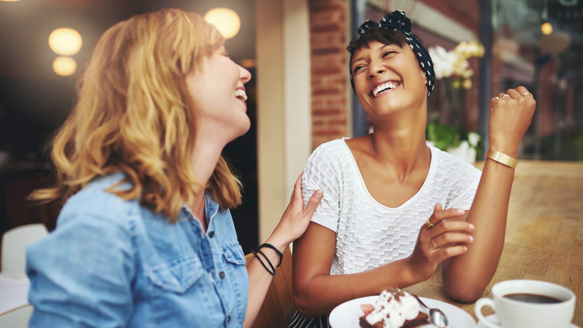 two women laughing while having coffee together