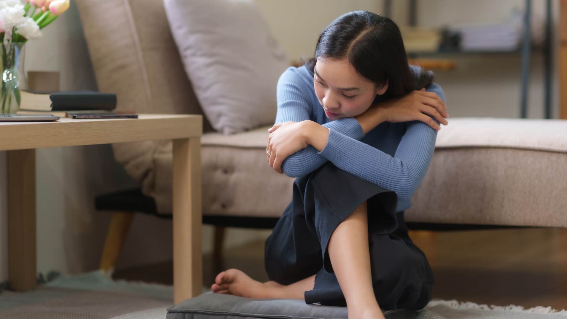 young woman feeling stressed sitting on floor