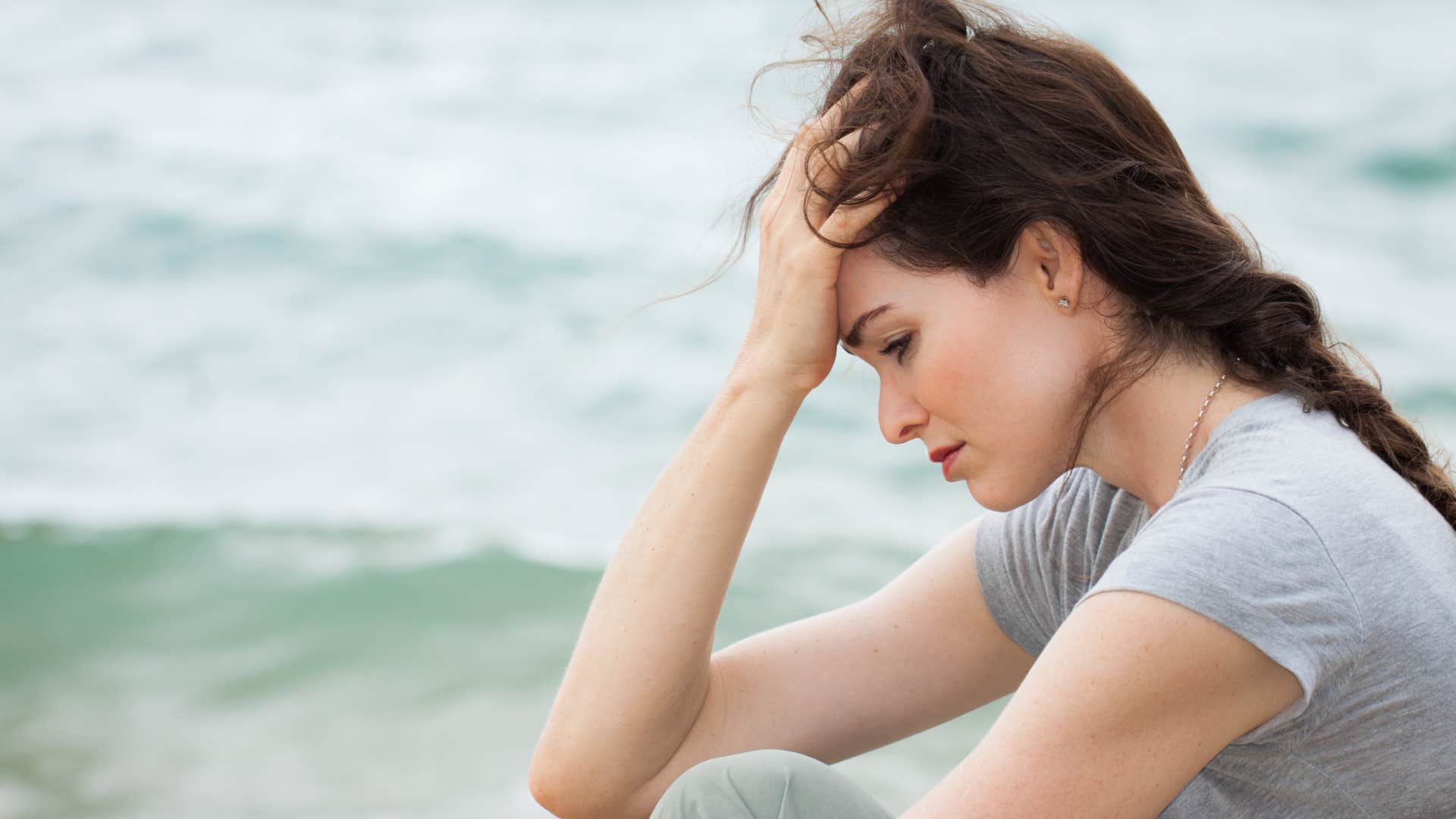 sad woman deep in thought by the ocean