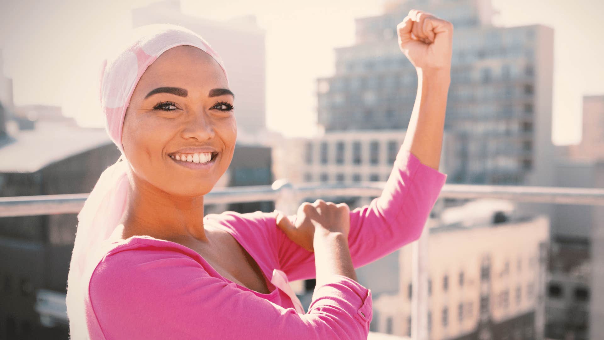 Confident woman raises a hopeful fist against city skyline