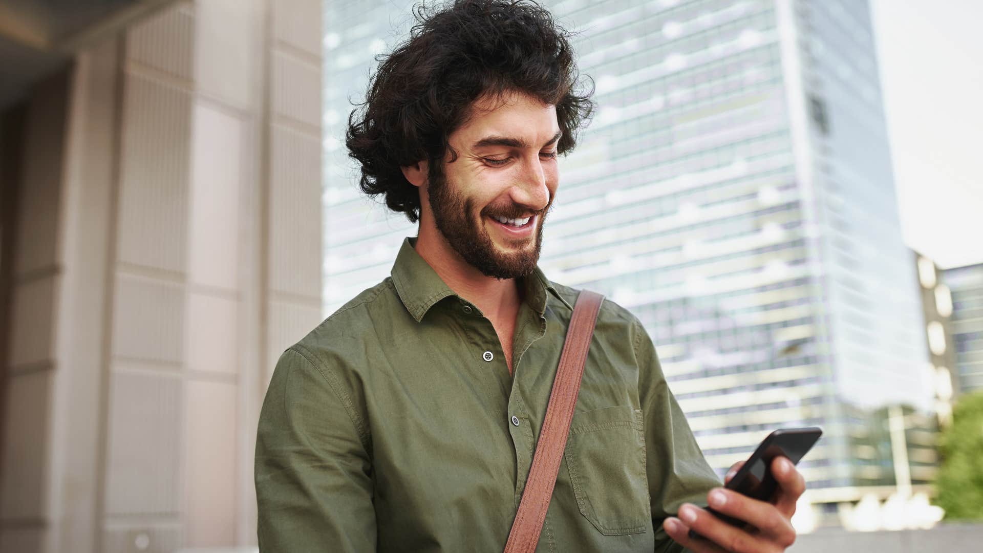 Man smiling while texting on his phone.