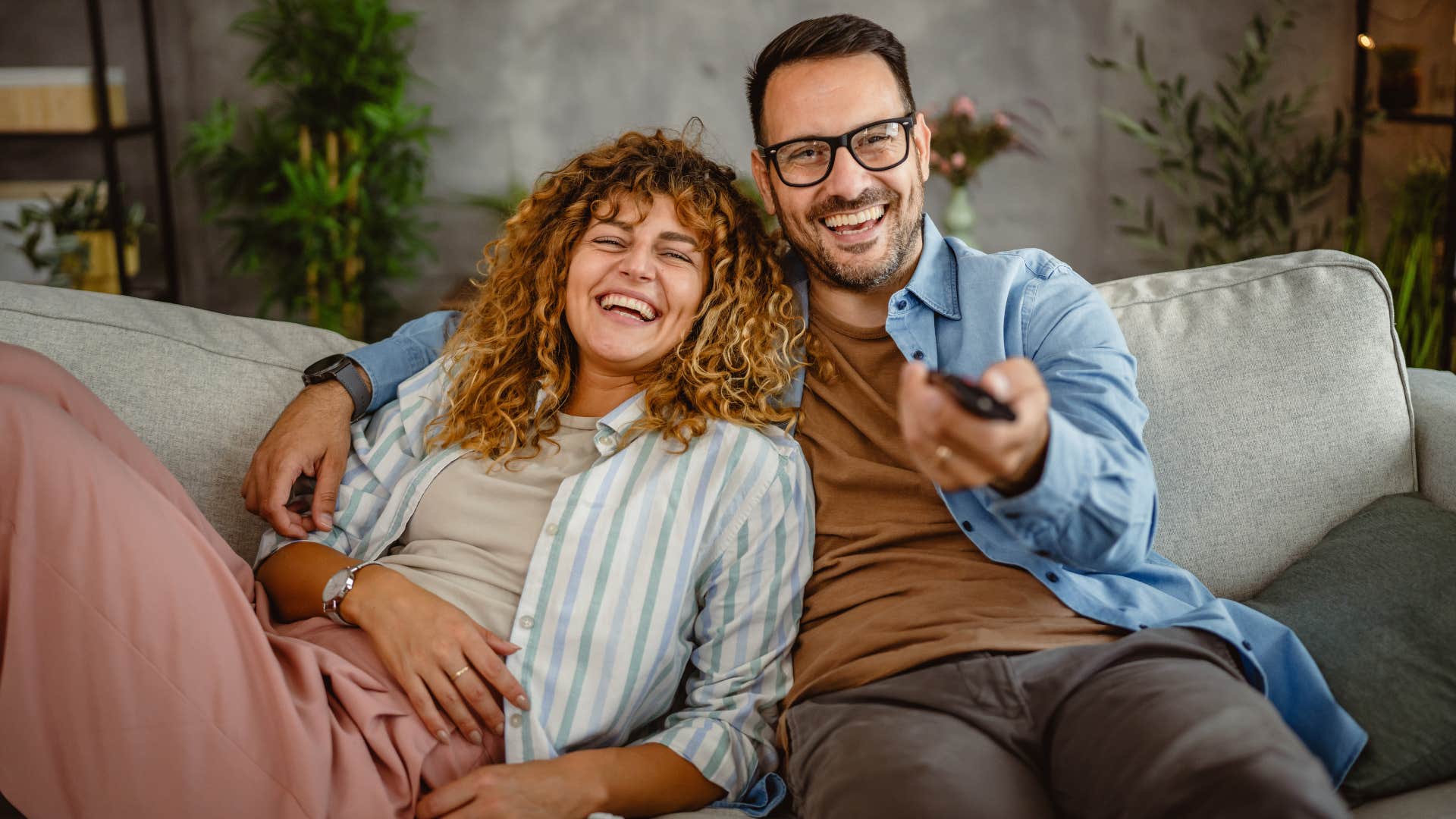 Couple smiling and watching TV together.