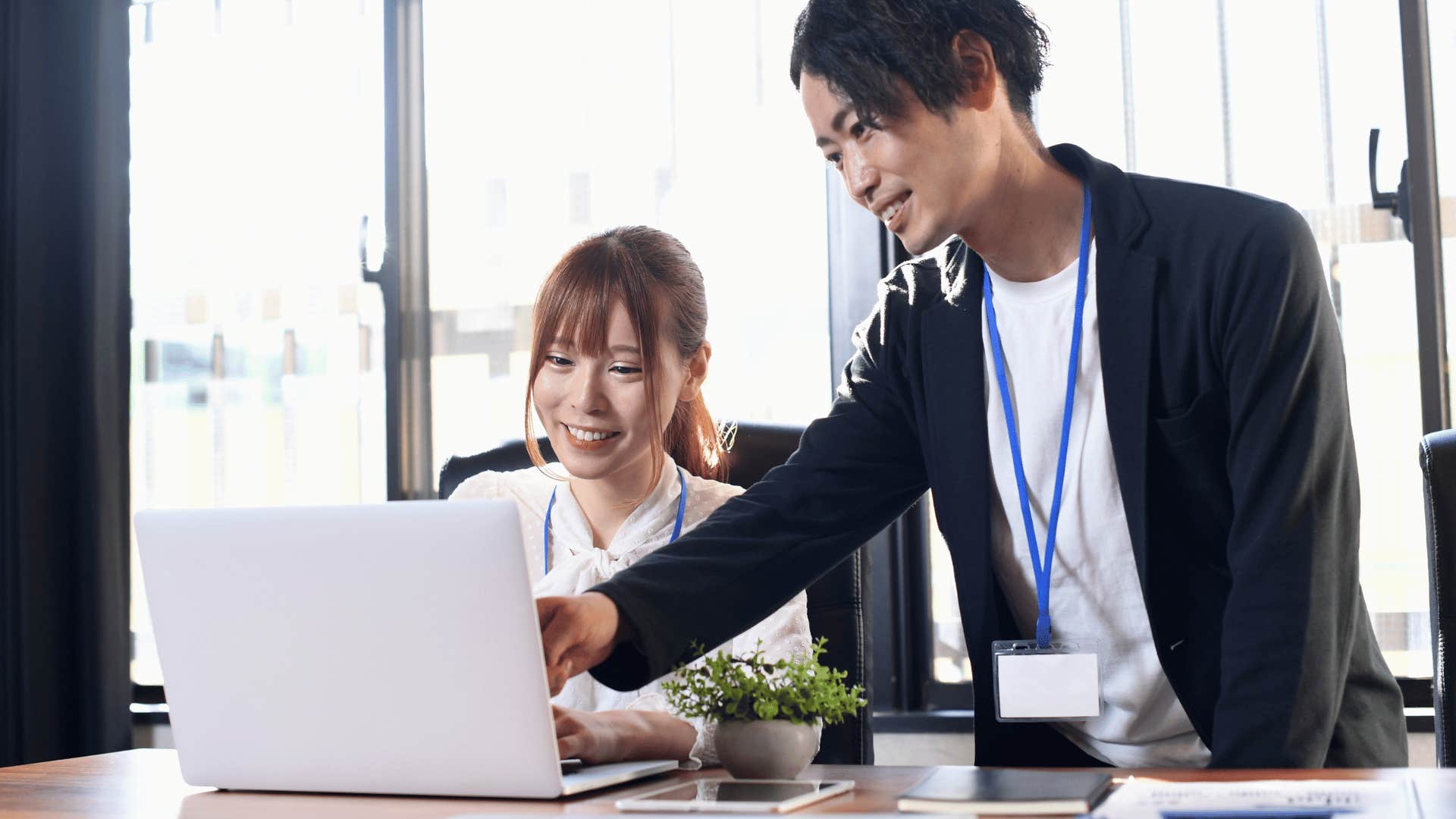 man teaching woman something on laptop