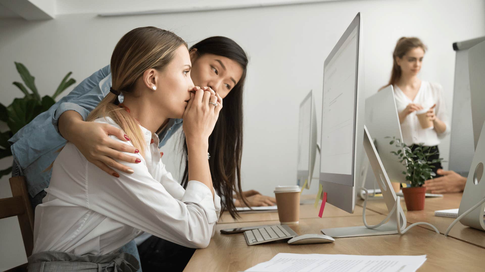 woman comforting other woman at desk