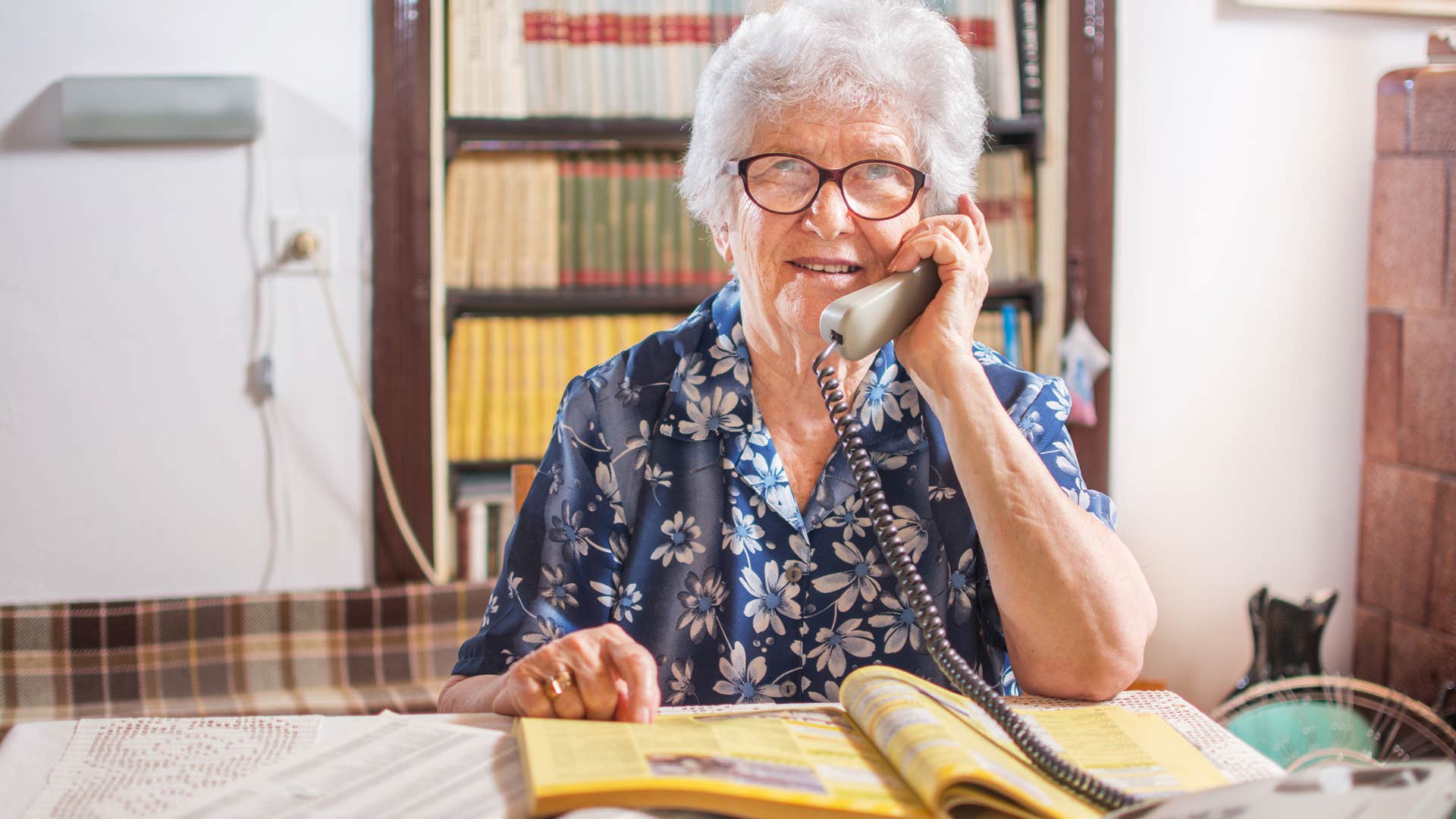 Elderly woman using a phone book which have disappeared without anyone noticing