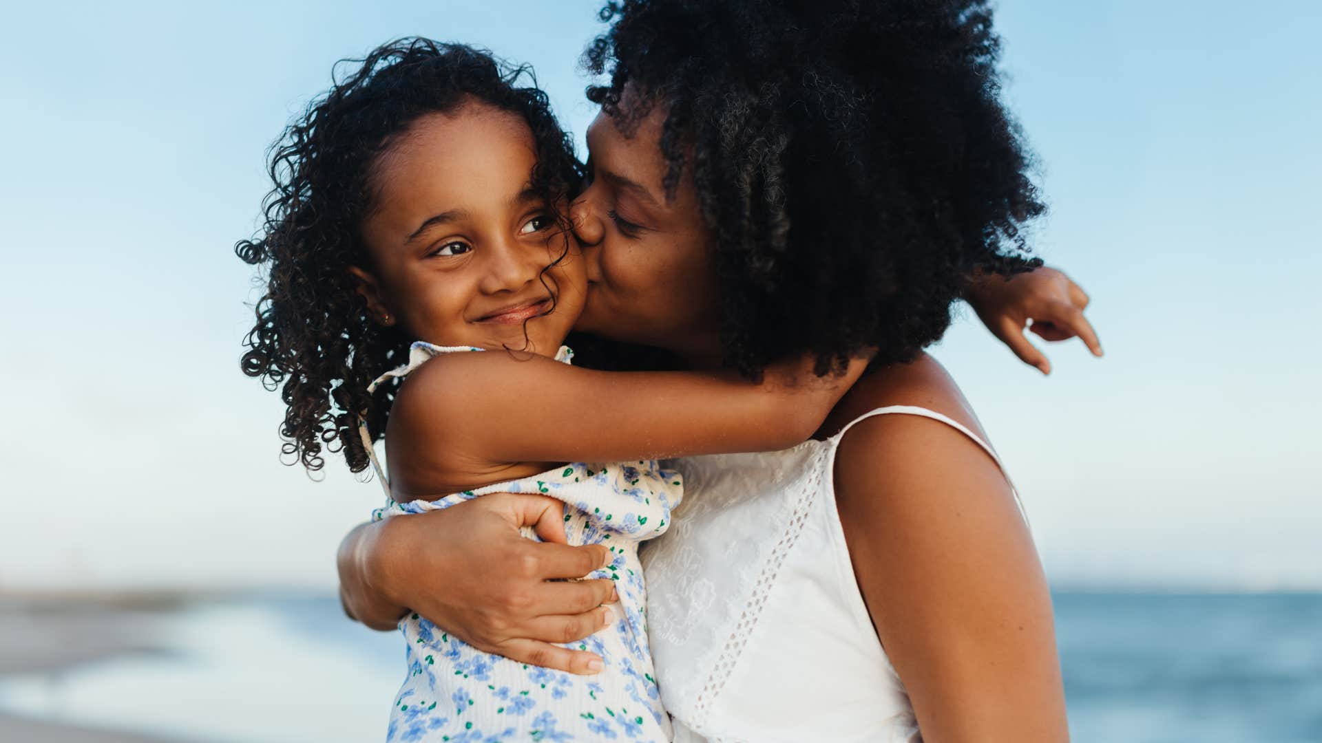 A loving mother embraces her daughter on the beach