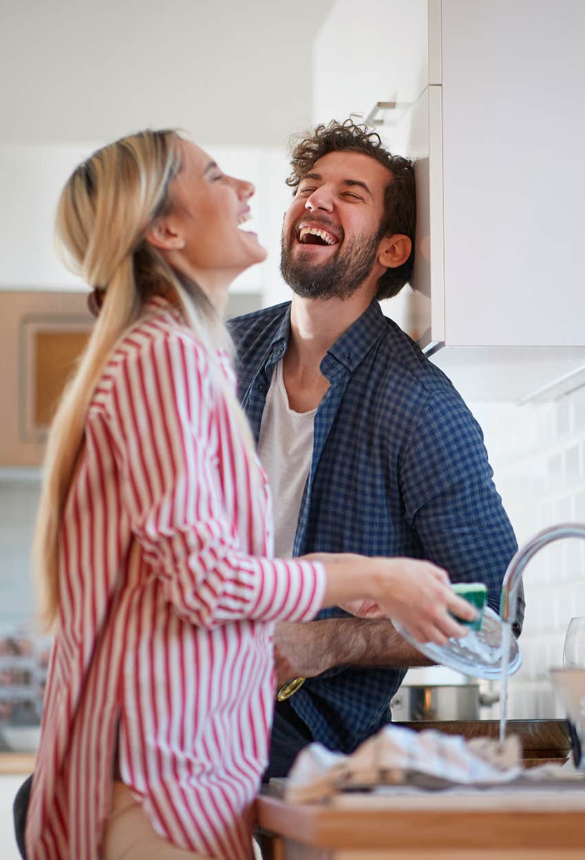 Happy couple finding joy and enthusiasm while washing dishes