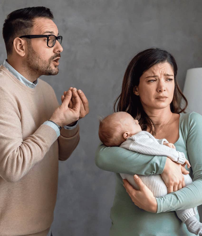 Egoistic man gestures annoyance at upset woman holding infant