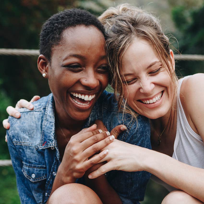 Two women hug, smile, and laugh