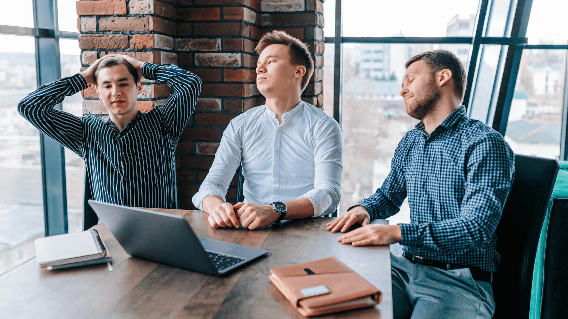 upset men sitting at table in office