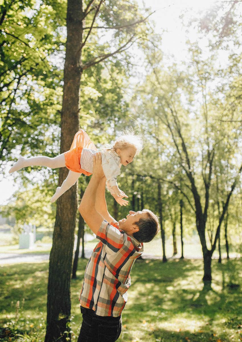 dad lifting up his daughter in the air outside