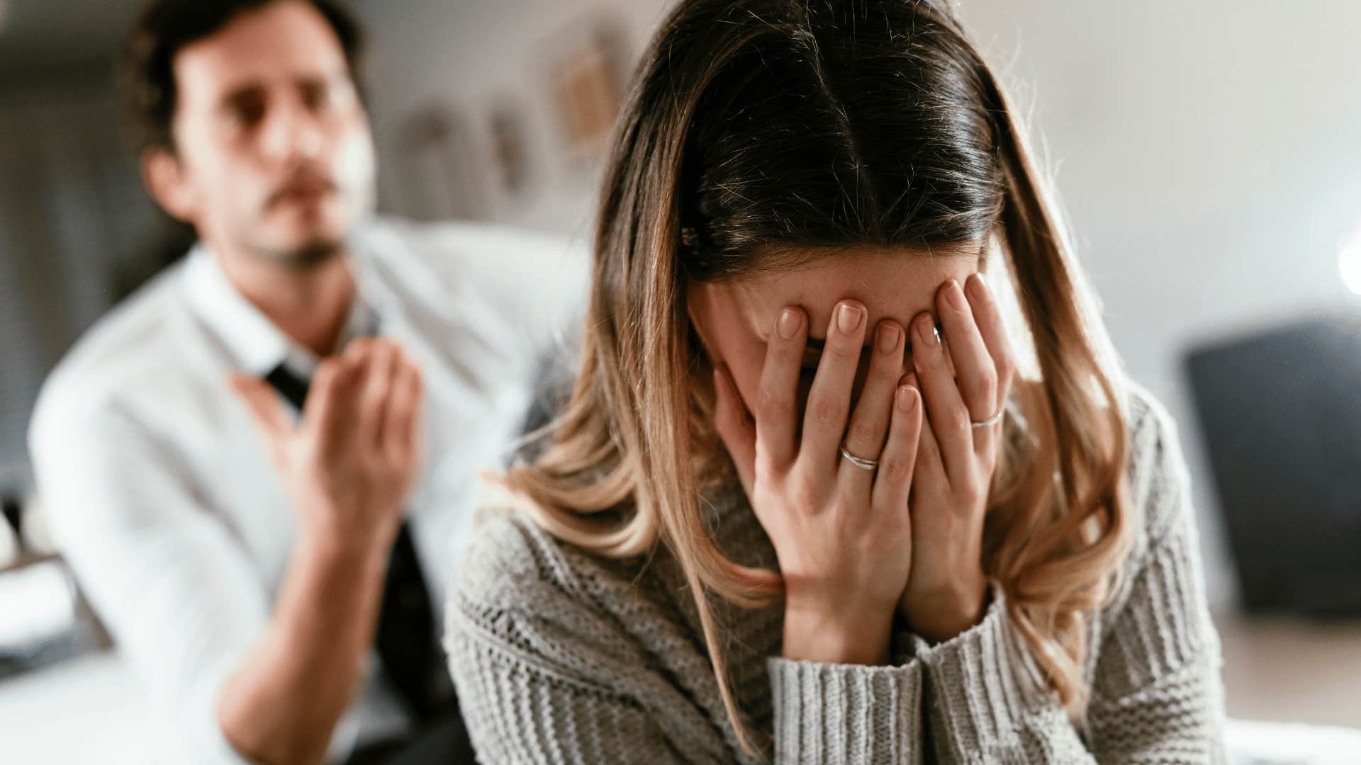 woman crying while man yells behind her