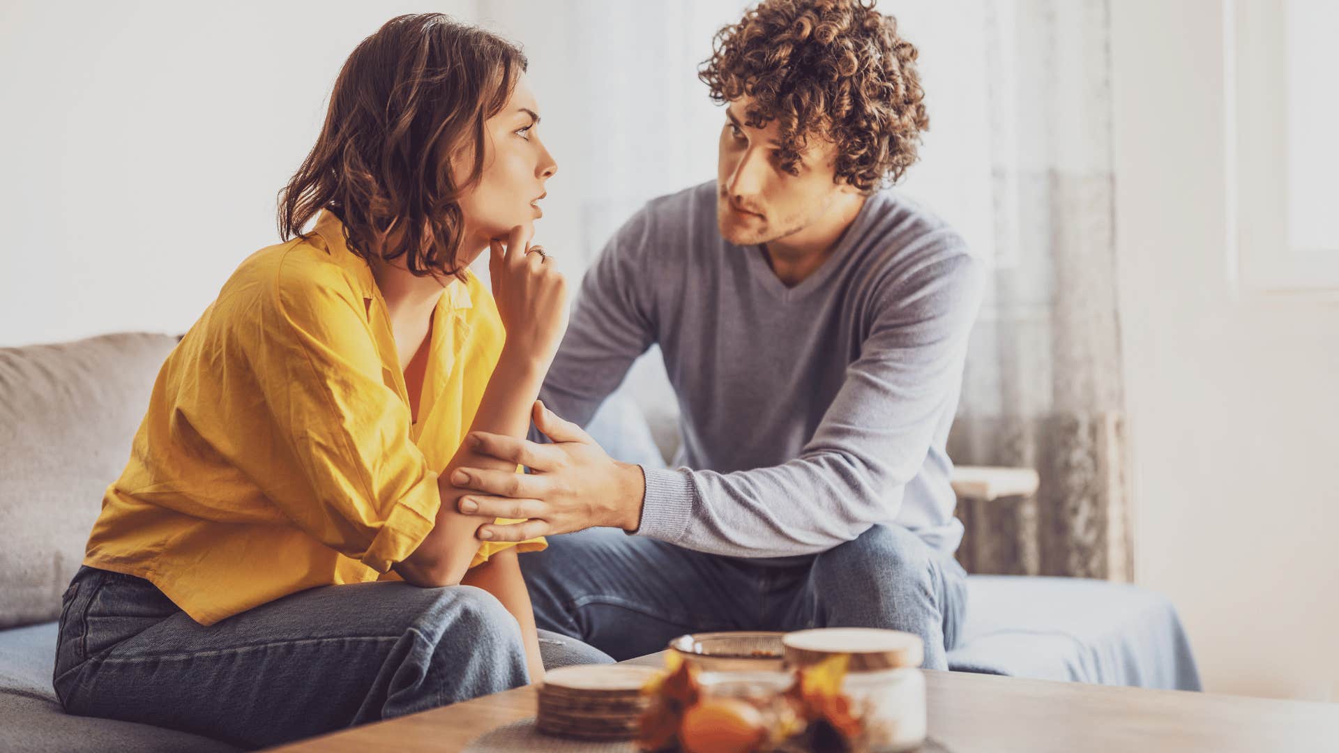 man comforting woman on couch