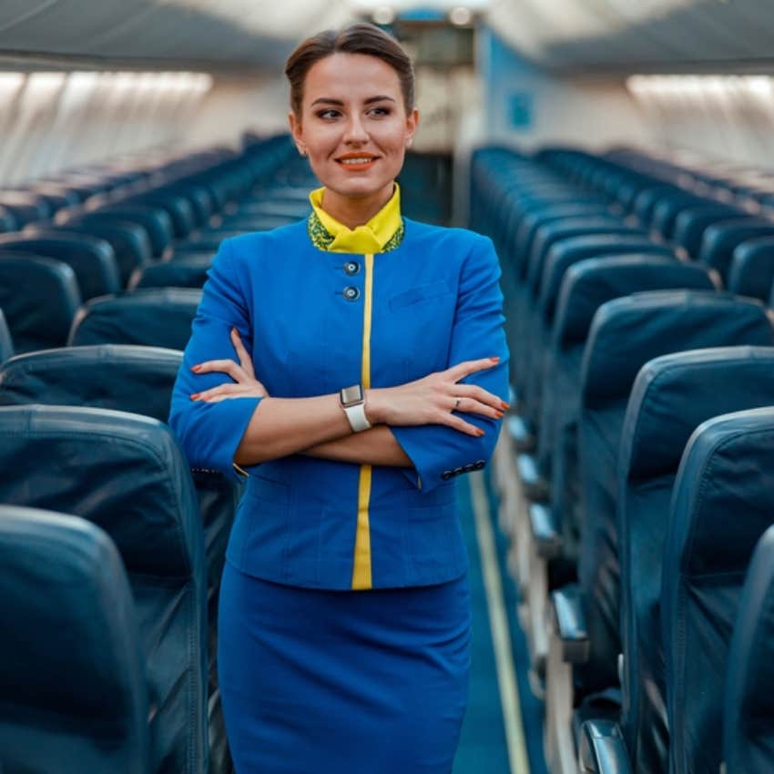 flight attendant standing in plane aisle 