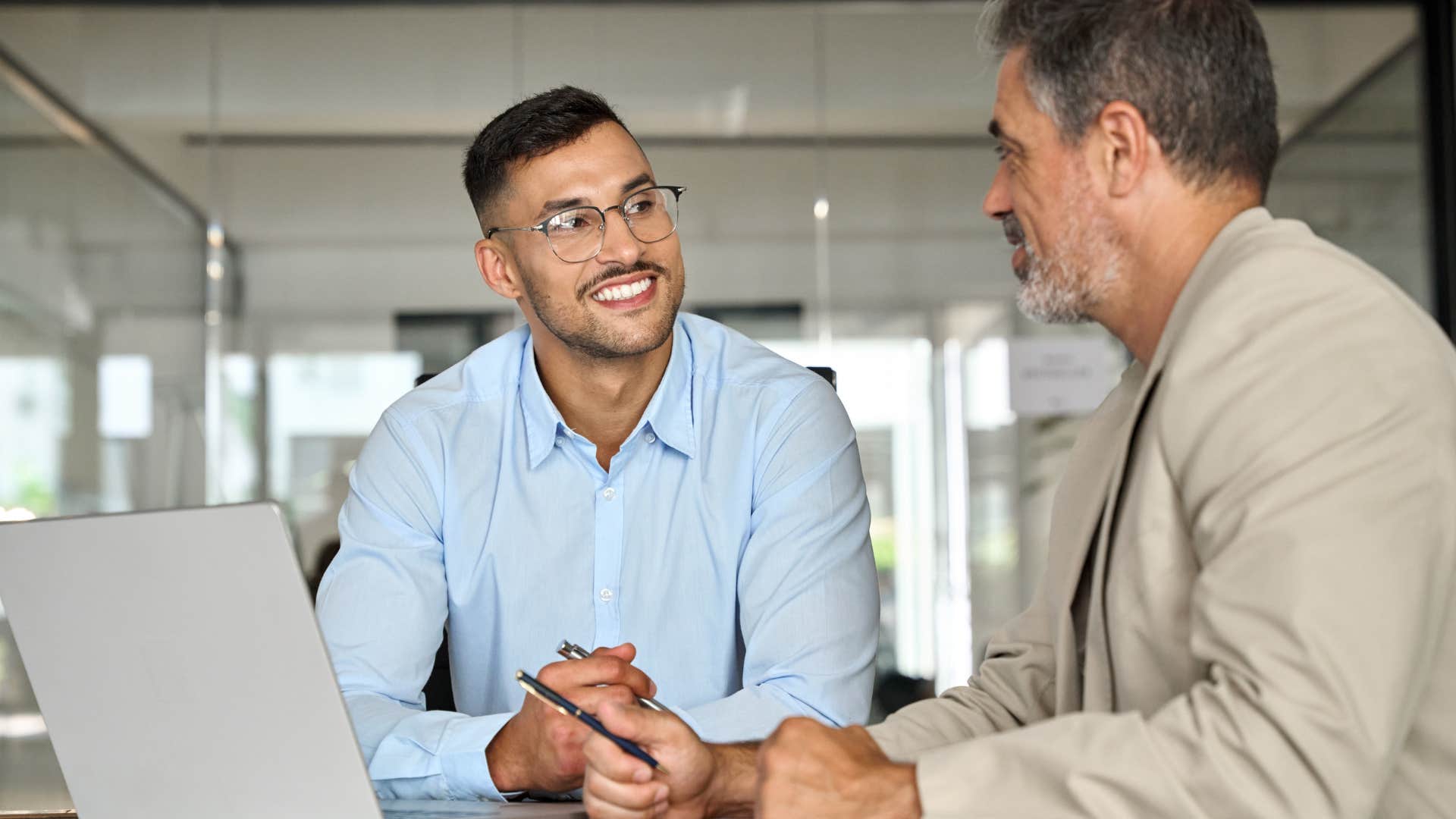 young man smiling talking to co-worker