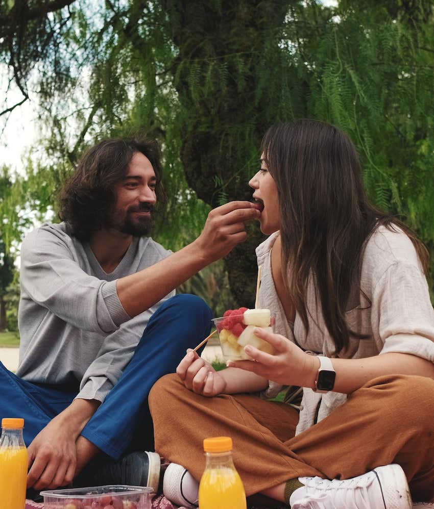 Man feeds woman at a surprise picnic in the park