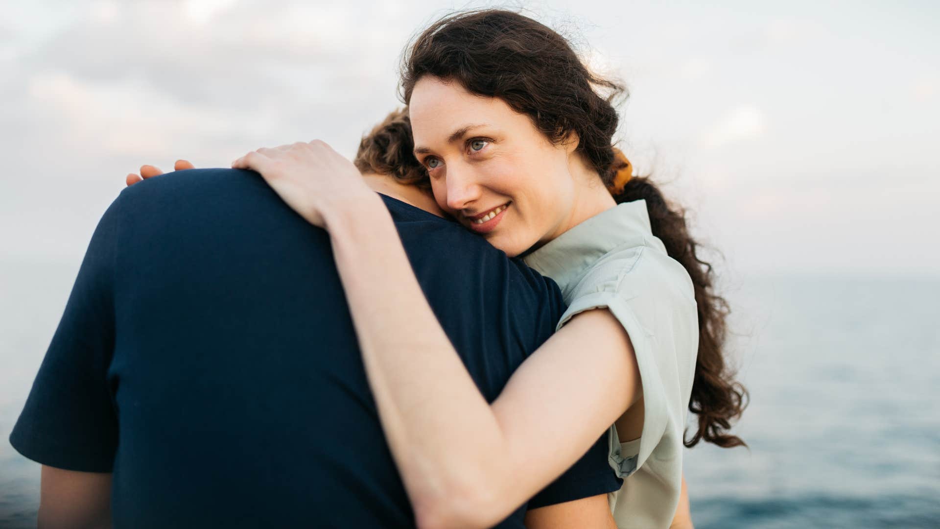 Couple embracing by the sea cares for her when she's sick