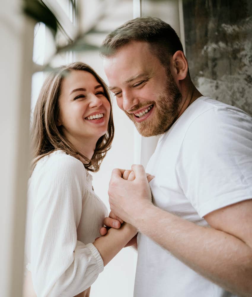 Couple laughing by a window, man getting what he needs