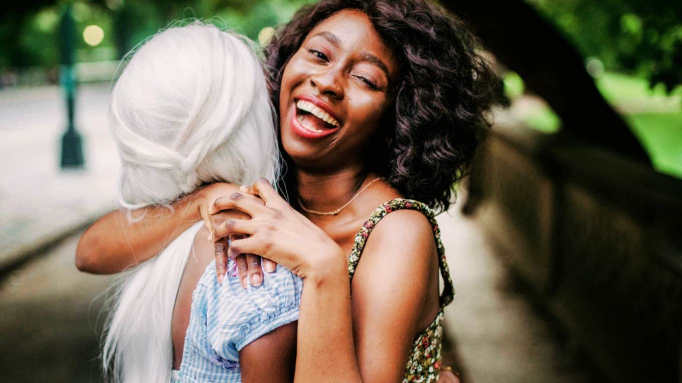 Joyful Black woman with a fun life hugging a friend 