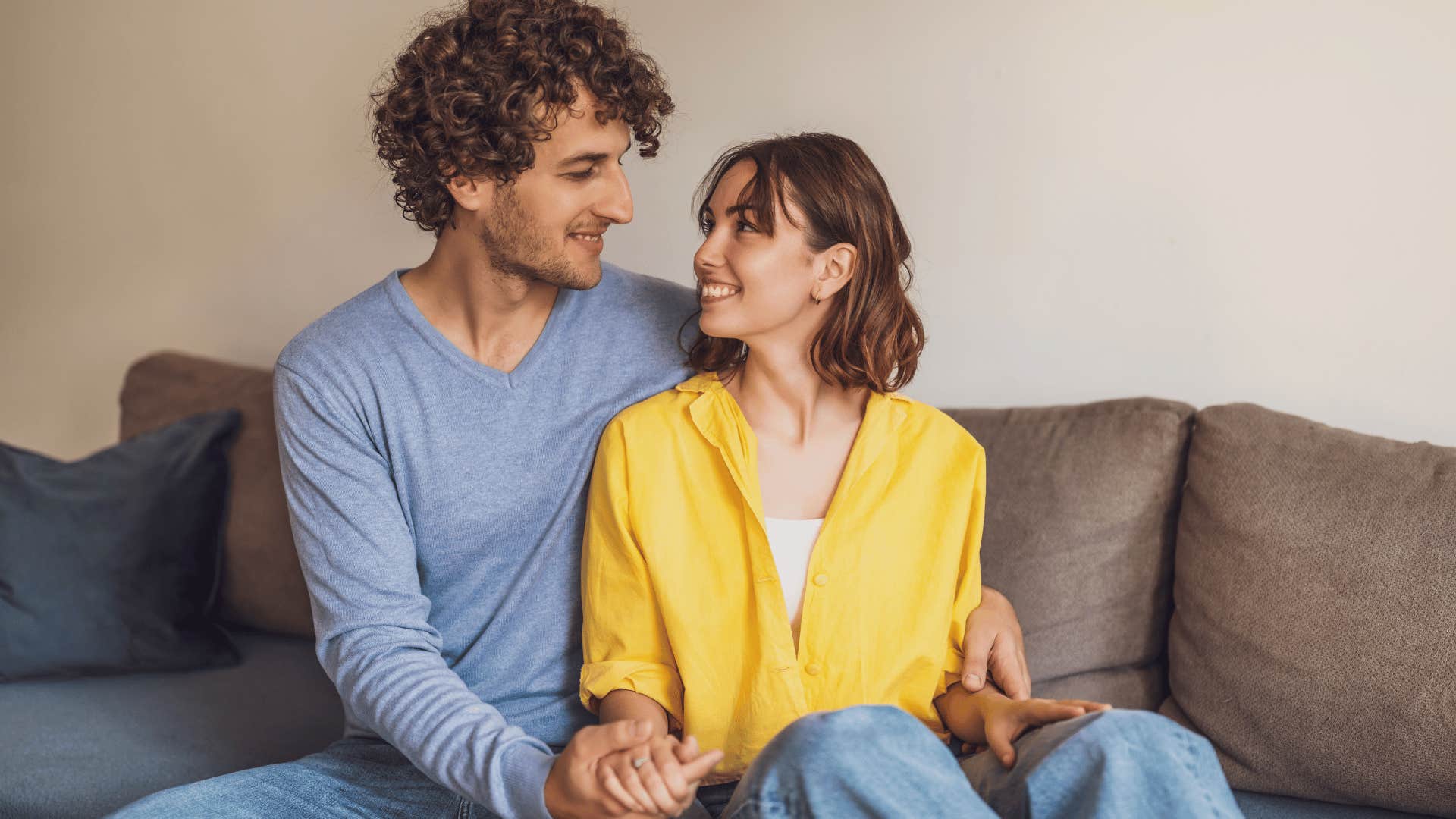 couple smiling and looking at each other on couch