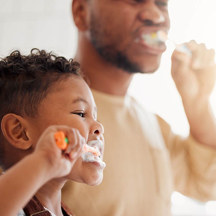 Father and child brush teeth together