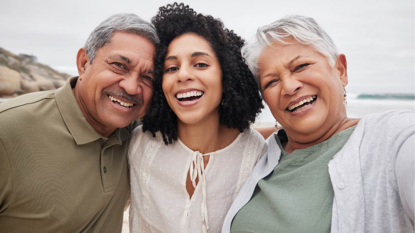 woman and senior parents at beach on holiday