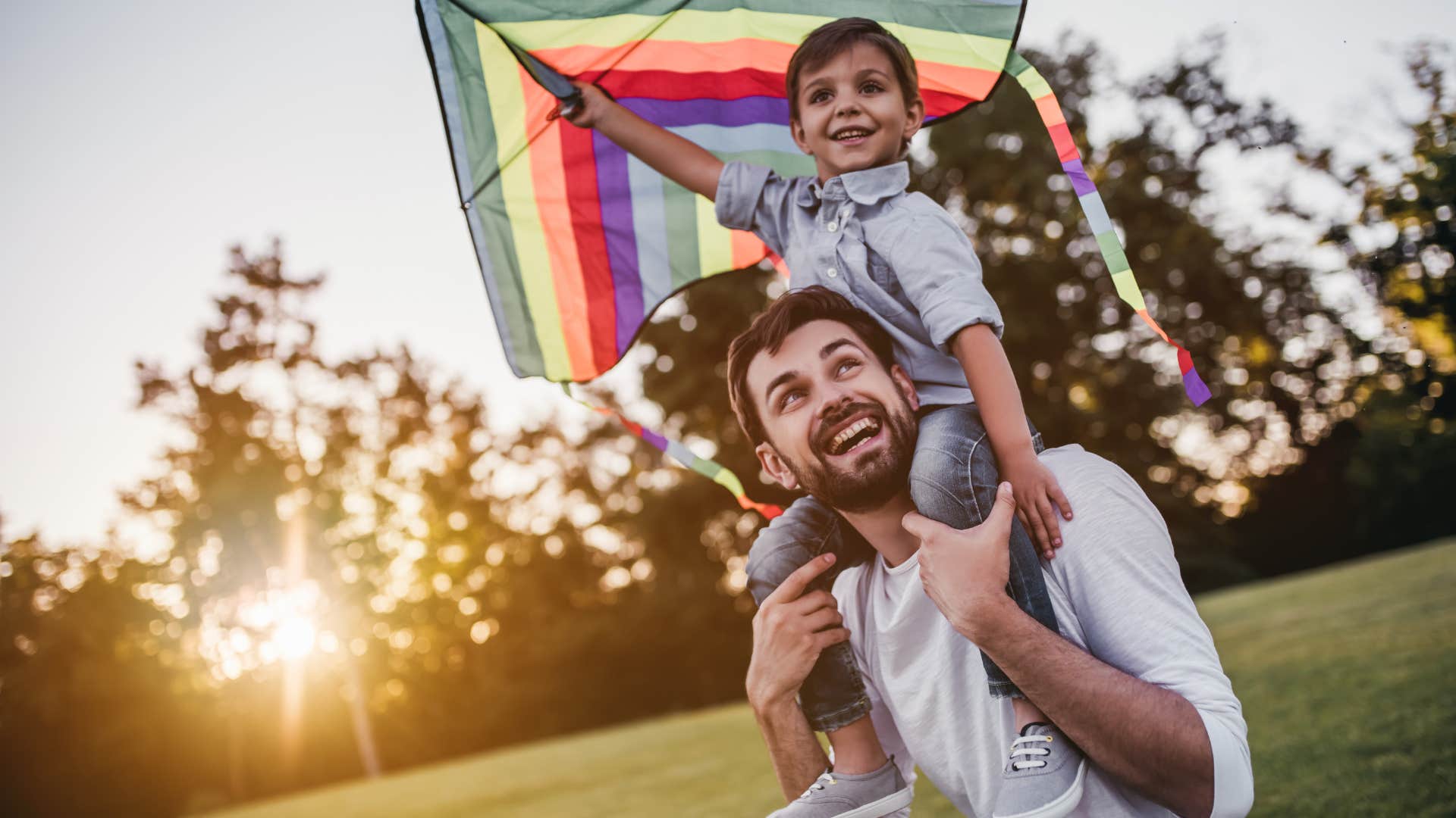 dad holding young son with a kite