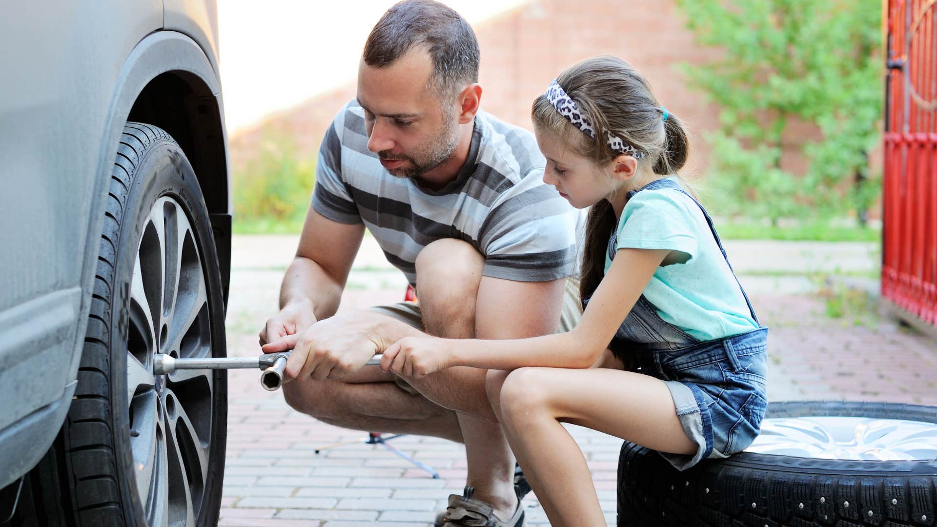 dad teaching daughter to change a tire