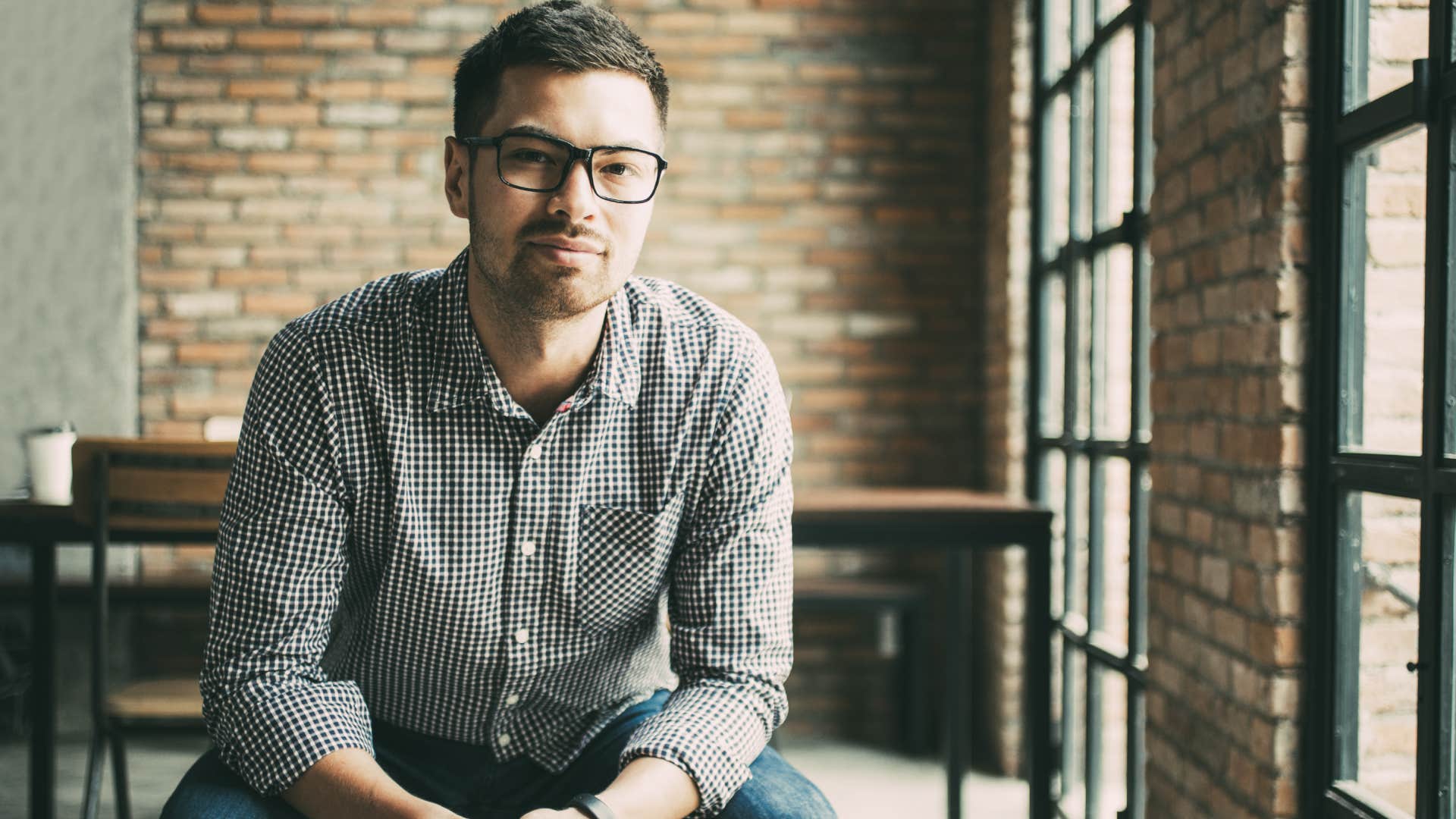 Friendly Man Sitting at Window in Loft Cafe