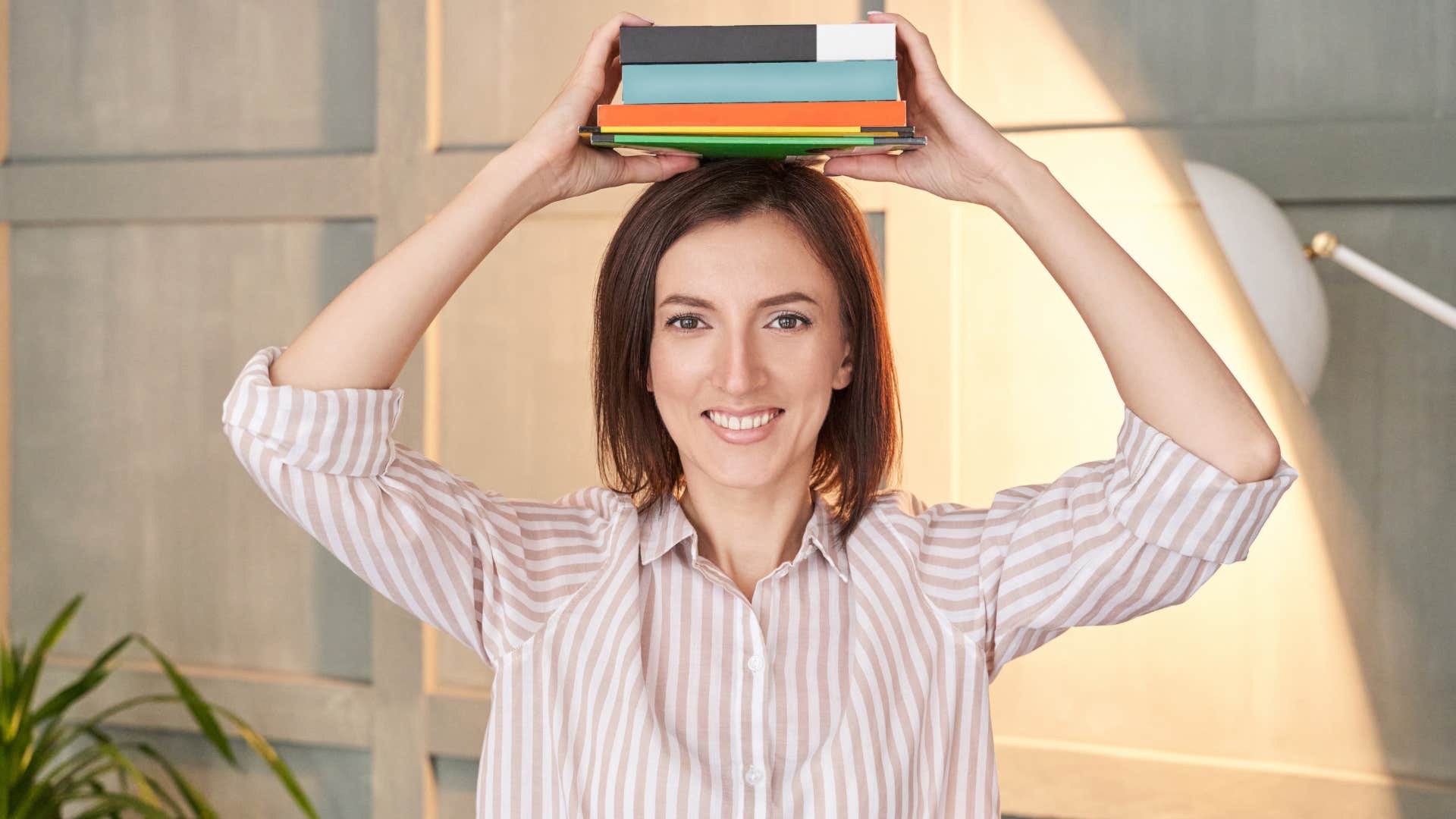 woman showing poise by balancing books on her head to project powerful elegance and sophistication