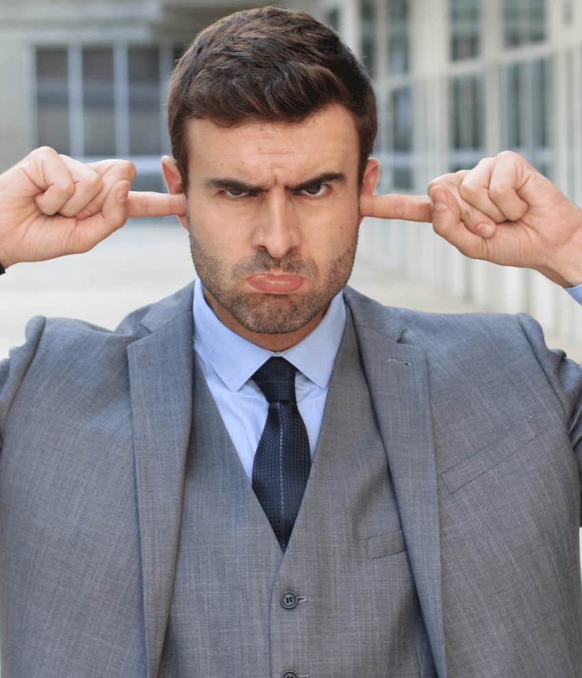 Childish business man makes face and puts fingers in his ears to manage rage