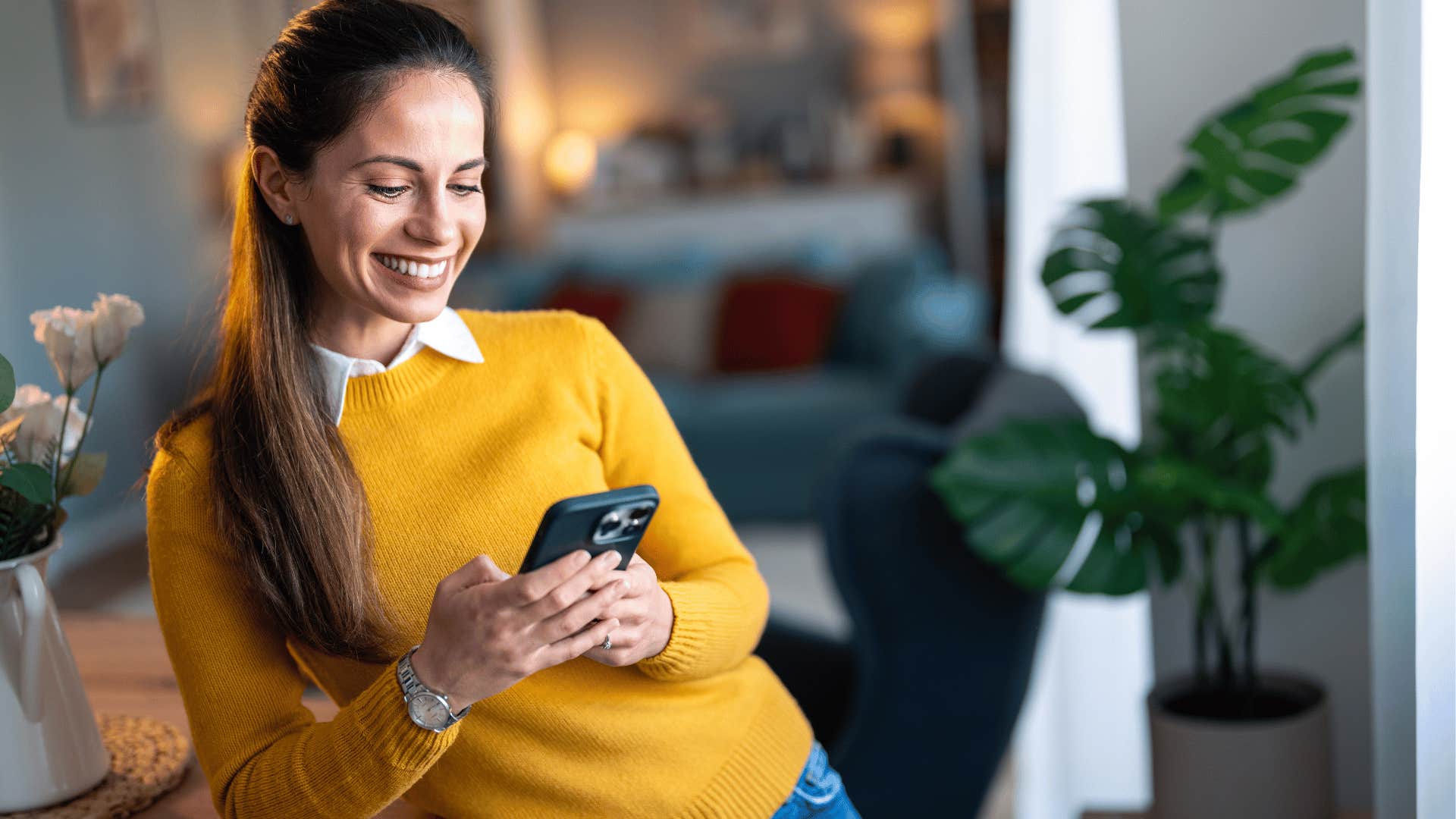 woman smiling while looking at phone