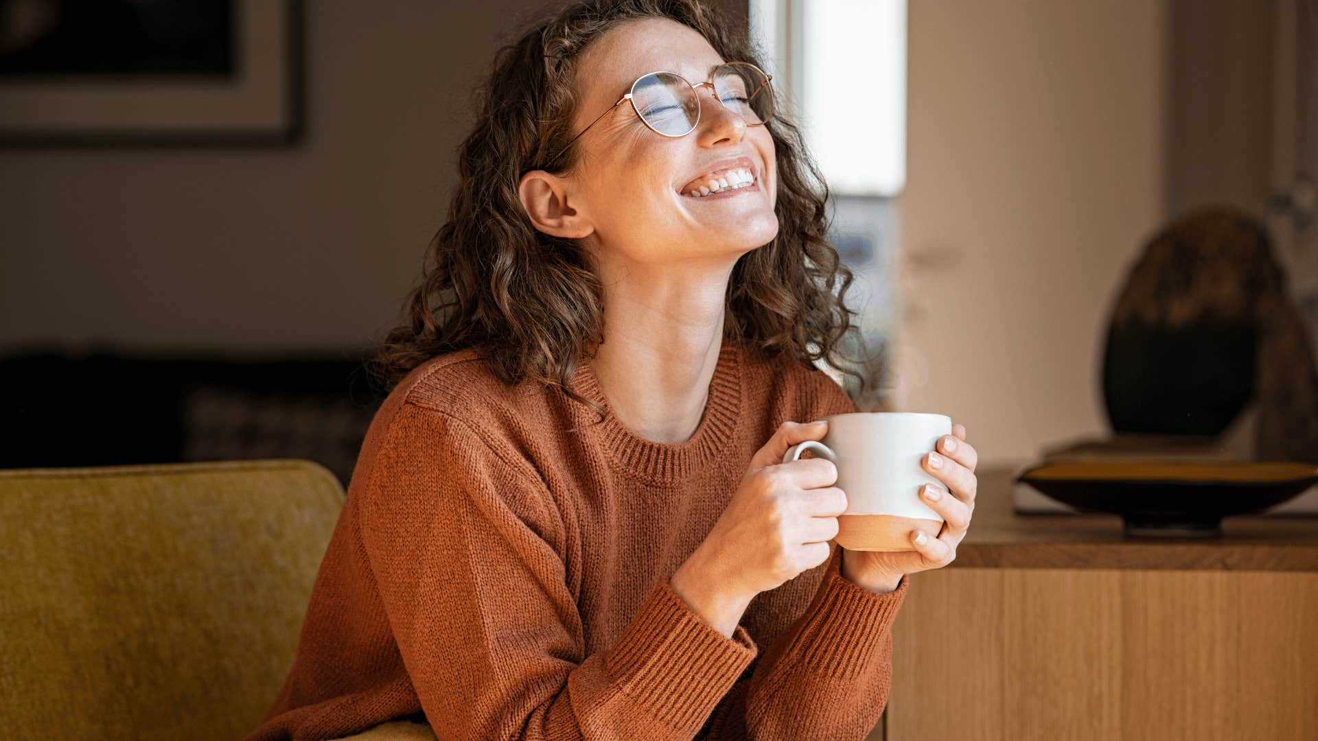 woman smiling while drinking coffee