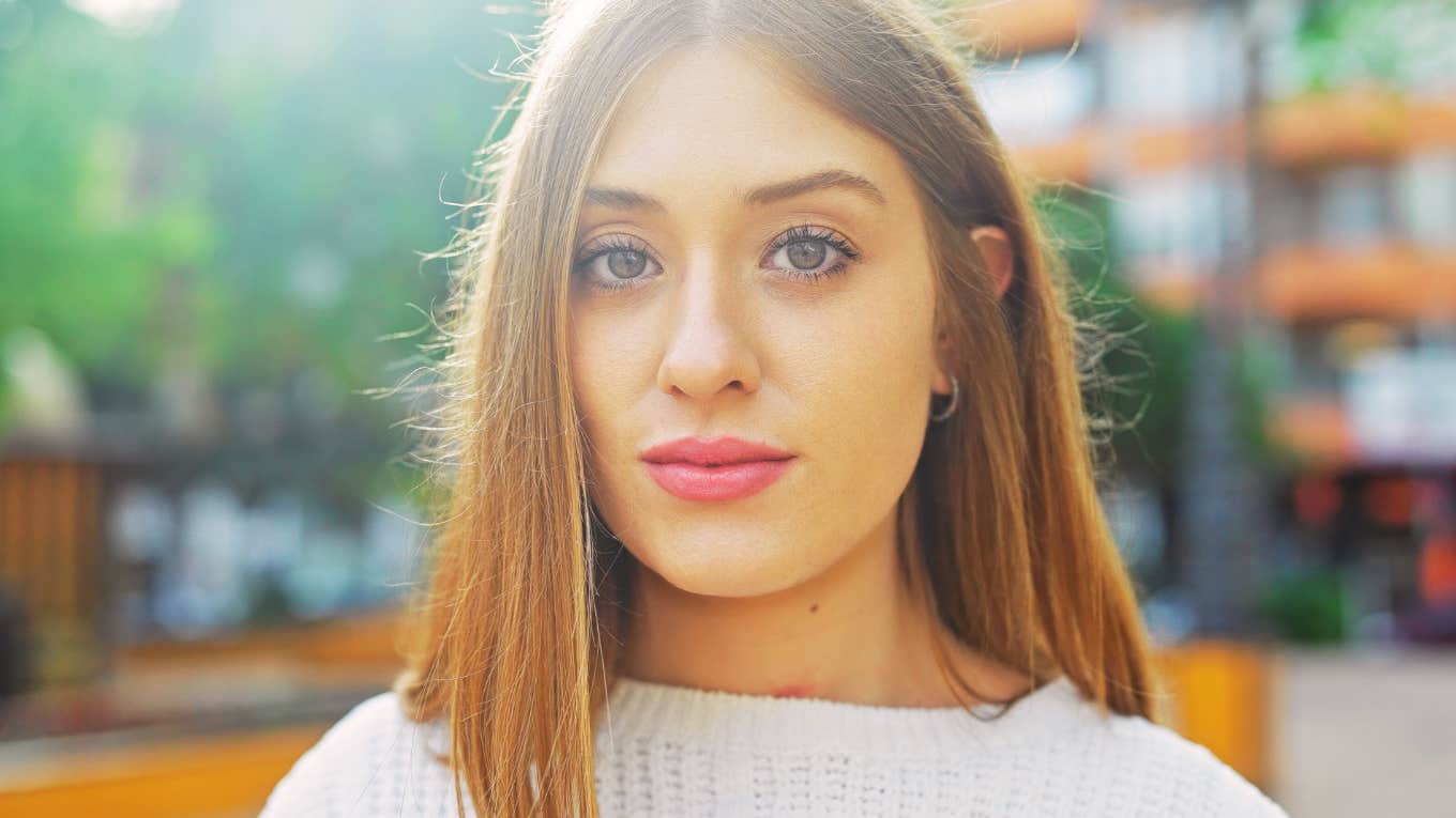 A young woman poses outdoors in a city